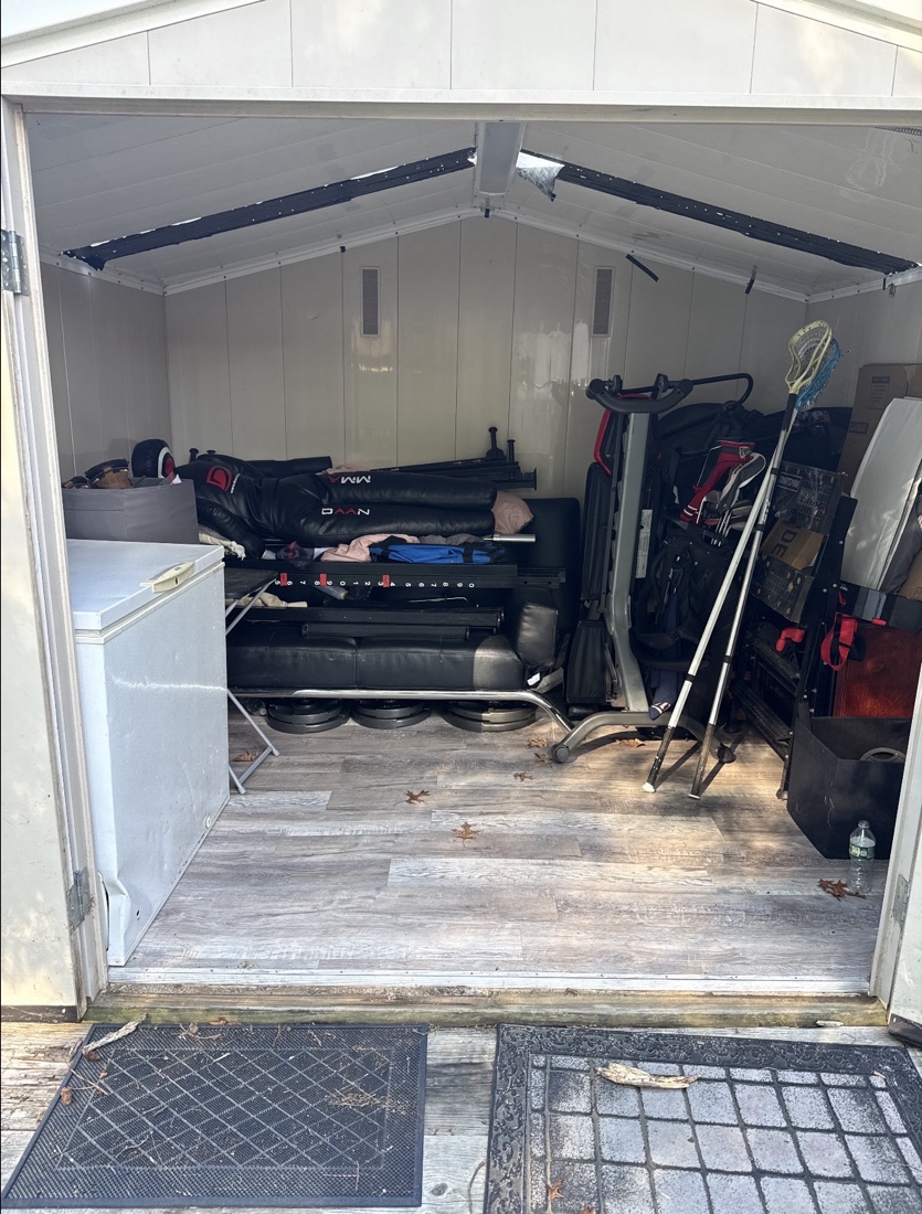 Before shed cleanout in Edison, NJ: a backyard shed packed with a freezer, gym equipment and sports gear
